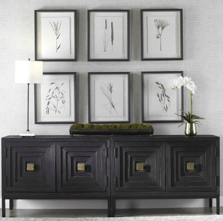 A black sideboard with framed pictures on it.